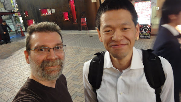 a white bearded man next to a slightly taller japanese man
